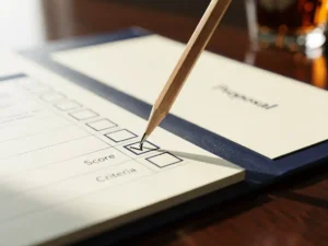 Scherp potlood dat een beoordelingsrubric invult op een evaluatieformulier, naast een openliggend voorstel op een vergadertafel.